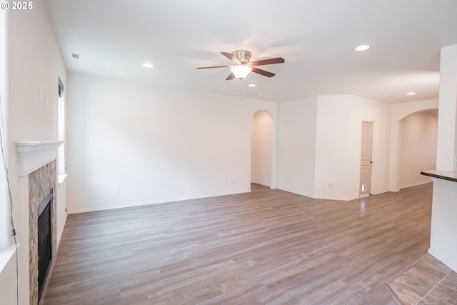 1067 S 55th St, Springfield, OR 97478 - unfurnished living room with arched walkways, a ceiling fan, recessed lighting, a tiled fireplace, and wood finished floors