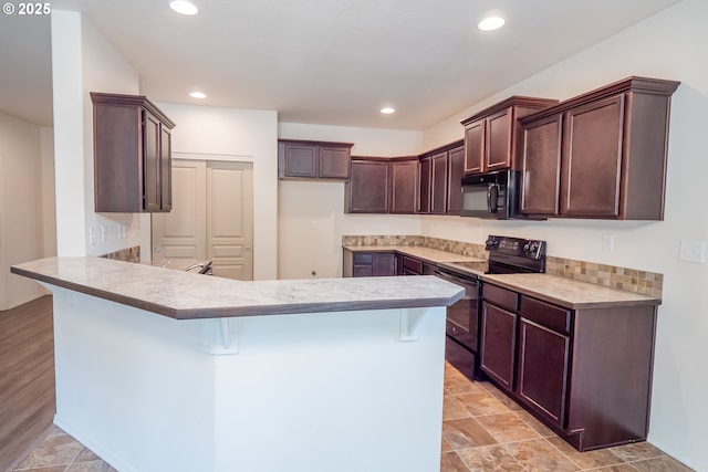 1067 S 55th St, Springfield, OR 97478 - kitchen featuring black appliances, a peninsula, light countertops, a kitchen breakfast bar, and dark brown cabinets