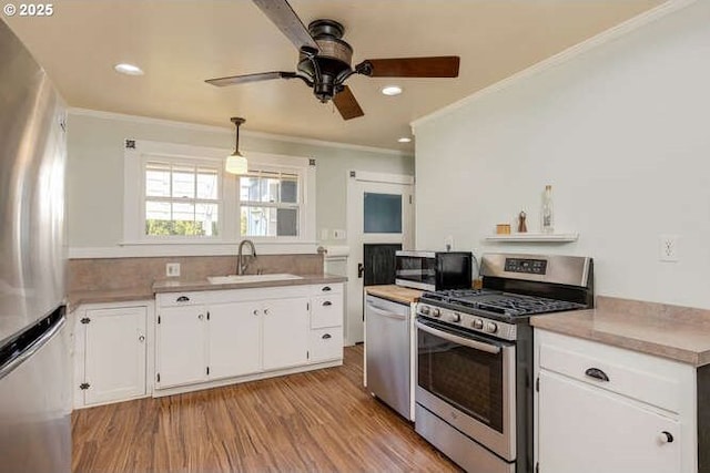 709 S Meridian St, Newberg, OR 97132 - kitchen featuring stainless steel appliances, ceiling fan, crown molding, light wood-style flooring, and white cabinets