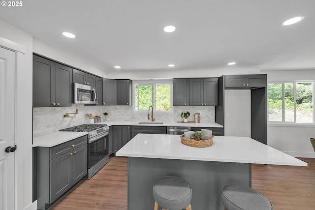 37465 Dubarko Rd, Sandy, OR 97055 - kitchen with appliances with stainless steel finishes, a breakfast bar area, wood finished floors, and recessed lighting