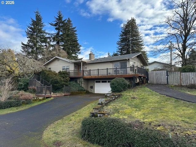 view of front of house featuring a garage, aphalt driveway, fence, a deck, and a front yard