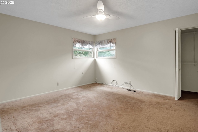 carpeted spare room with a ceiling fan, baseboards, and a textured ceiling