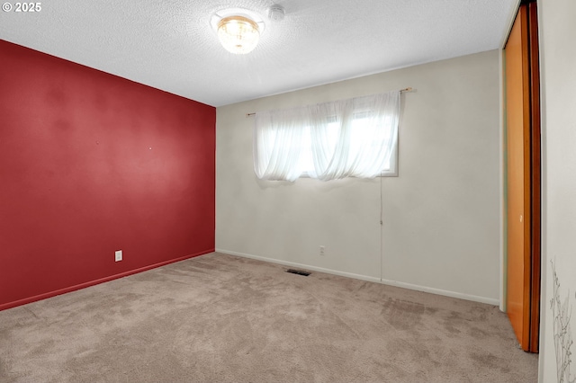 carpeted empty room with visible vents, baseboards, and a textured ceiling