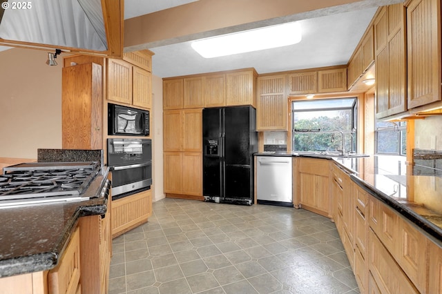 kitchen with tasteful backsplash, light brown cabinets, dark stone countertops, black appliances, and a sink