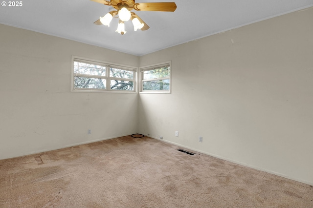 carpeted spare room with visible vents, plenty of natural light, and ceiling fan