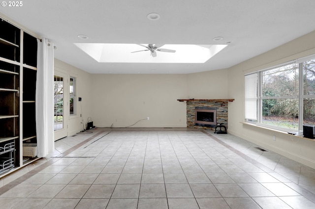 unfurnished living room featuring light tile patterned floors, a skylight, a raised ceiling, and a wealth of natural light