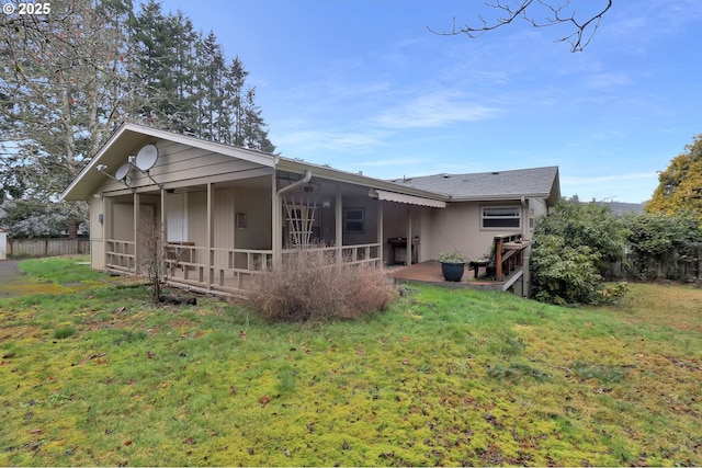 rear view of house featuring a lawn and fence