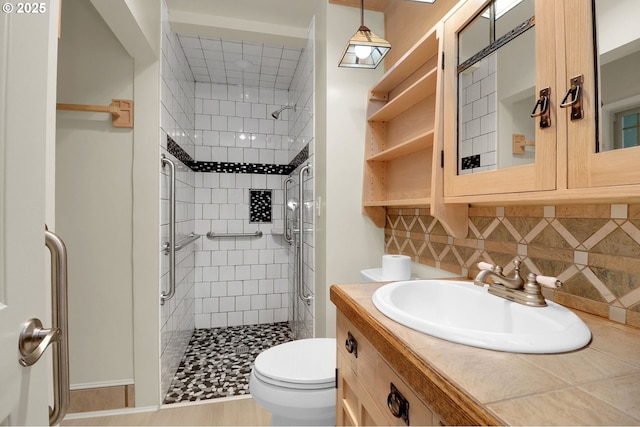 bathroom featuring tasteful backsplash, a stall shower, toilet, and vanity