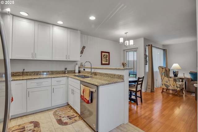 kitchen with stainless steel dishwasher, a peninsula, a sink, white cabinets, and recessed lighting