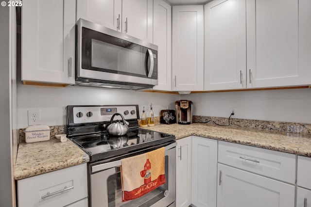 kitchen featuring appliances with stainless steel finishes, white cabinets, and light stone counters