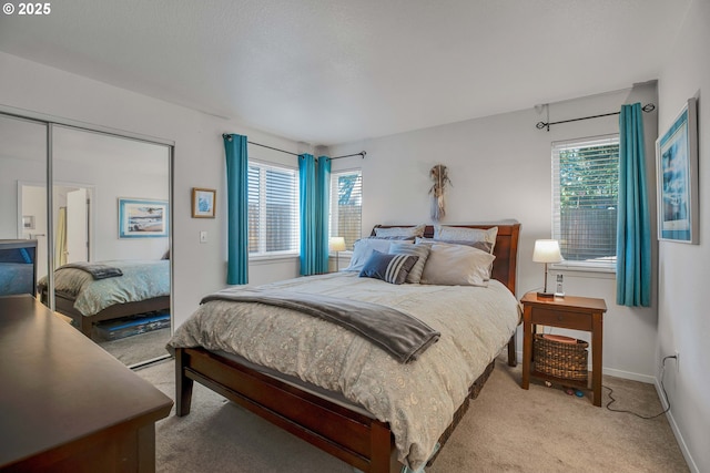 bedroom featuring light colored carpet, a closet, and baseboards