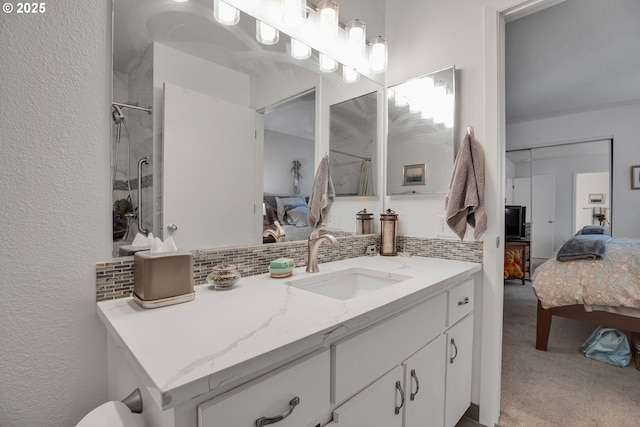 ensuite bathroom featuring tasteful backsplash, vanity, a textured wall, and a shower