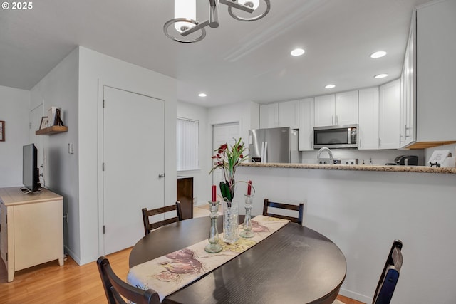 dining area with light wood-style floors, recessed lighting, and a chandelier