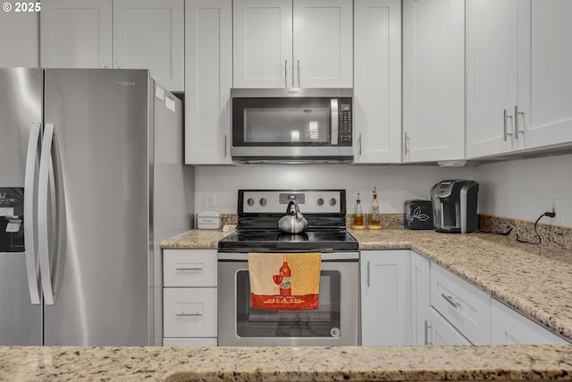kitchen with appliances with stainless steel finishes, white cabinets, and light stone counters