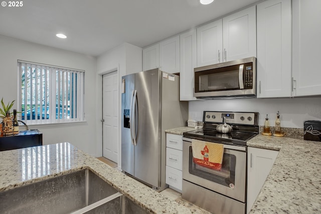 kitchen with stainless steel appliances, white cabinets, light stone counters, and recessed lighting