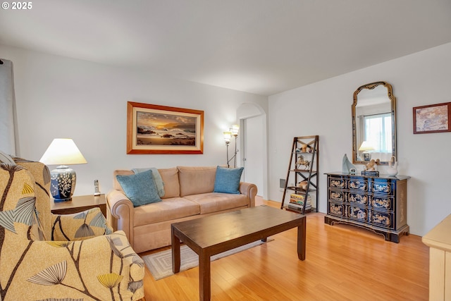 living room with arched walkways and light wood finished floors