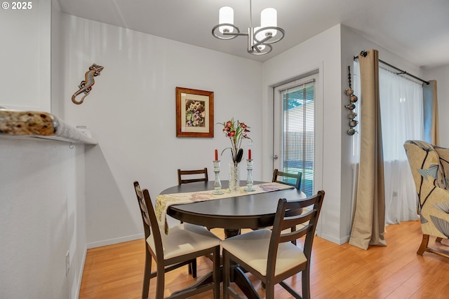 dining room with light wood-type flooring, a chandelier, and baseboards