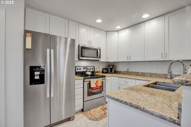 kitchen with appliances with stainless steel finishes, a sink, recessed lighting, white cabinets, and light stone countertops