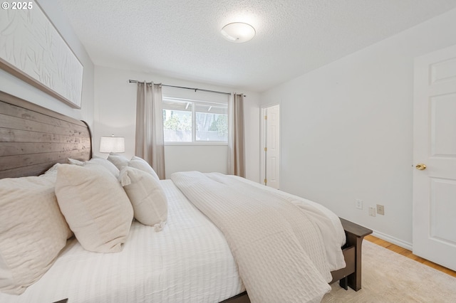 13440 SW Greenleaf Pl, Beaverton, OR 97005 - bedroom with light wood-style flooring, a textured ceiling, and baseboards