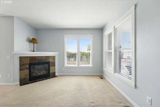 unfurnished living room featuring carpet floors, a tile fireplace, and baseboards