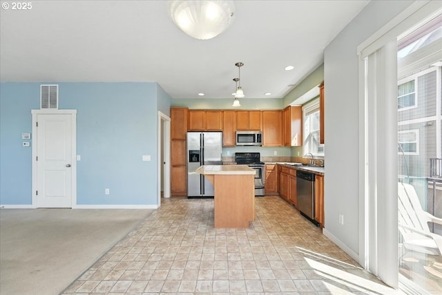 kitchen featuring stainless steel appliances, a center island, baseboards, a sink, and recessed lighting