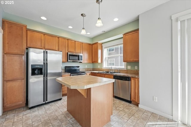 kitchen featuring stainless steel appliances, a sink, tile counters, a kitchen island, and hanging light fixtures