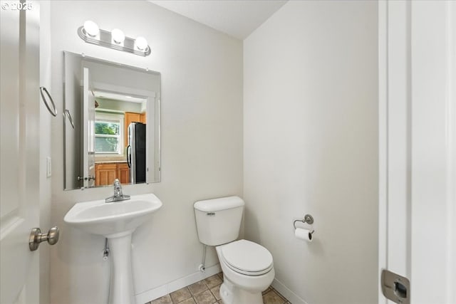 bathroom with baseboards, toilet, tile patterned flooring, and a sink