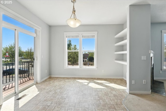 unfurnished dining area featuring plenty of natural light and baseboards