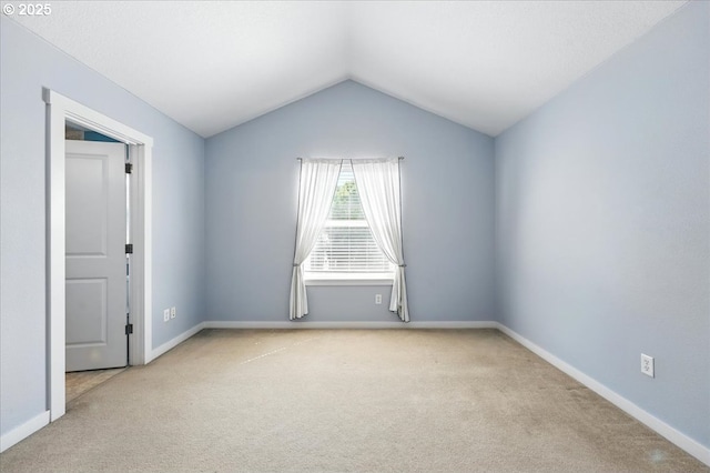empty room featuring carpet floors, lofted ceiling, and baseboards
