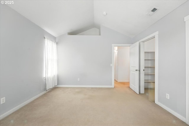 unfurnished bedroom with vaulted ceiling, carpet floors, a spacious closet, and baseboards