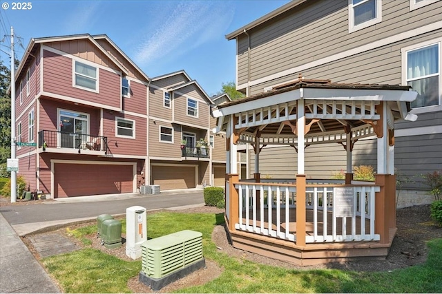view of yard with an attached garage, concrete driveway, and a gazebo
