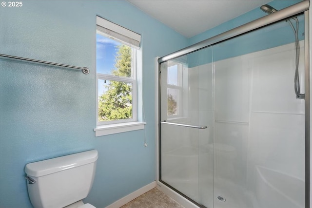 full bath featuring a stall shower, toilet, baseboards, and tile patterned floors