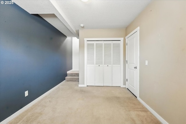 unfurnished bedroom with carpet, a closet, baseboards, and a textured ceiling