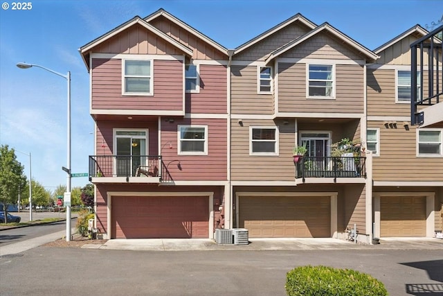multi unit property featuring board and batten siding, an attached garage, driveway, and cooling unit