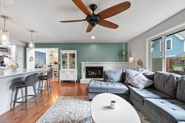 living room with a textured ceiling, ceiling fan, recessed lighting, and wood finished floors