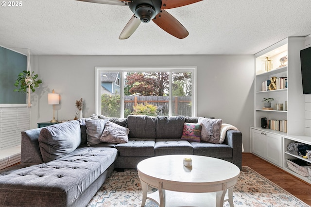 living area featuring a ceiling fan, a textured ceiling, and wood finished floors