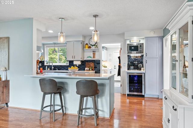 kitchen with open shelves, wine cooler, a kitchen bar, and tasteful backsplash