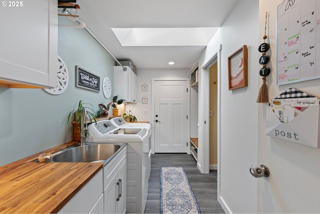 clothes washing area with dark wood finished floors, recessed lighting, washing machine and clothes dryer, cabinet space, and a skylight