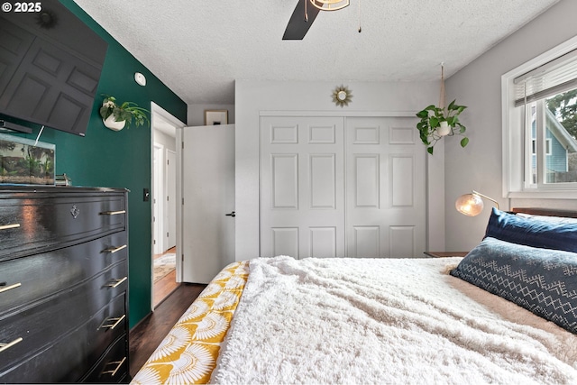 bedroom featuring a textured ceiling, dark wood finished floors, ceiling fan, and a closet