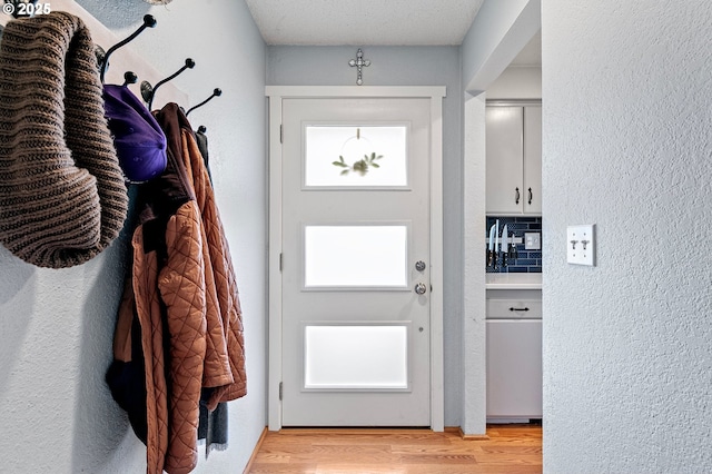 doorway to outside featuring a textured wall and light wood-style floors