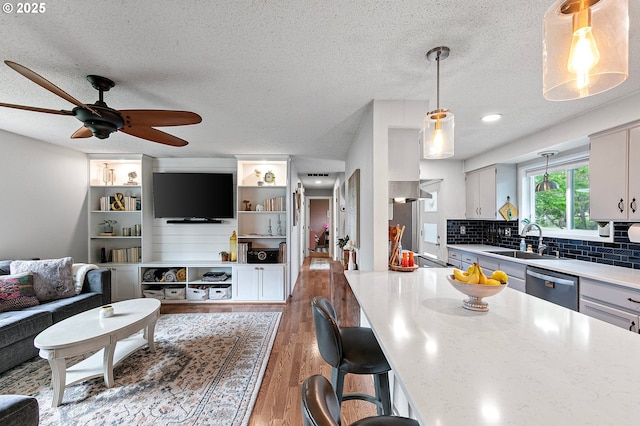kitchen with ceiling fan, a sink, dishwasher, light countertops, and light wood-style flooring