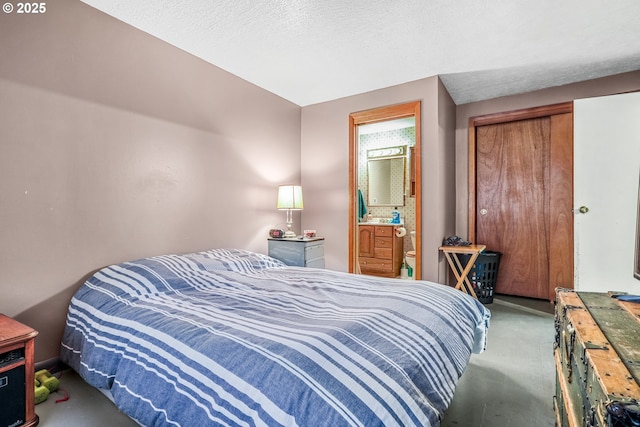 carpeted bedroom with connected bathroom and a textured ceiling