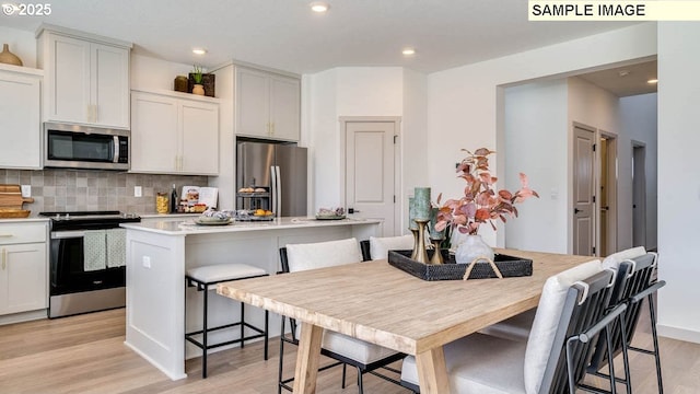 1518 W 14th Ave, La Center, WA 98629 - kitchen featuring stainless steel appliances, backsplash, light wood-style floors, a kitchen island, and a breakfast bar area