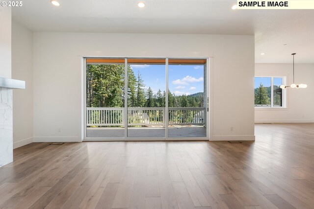 unfurnished living room featuring light hardwood / wood-style flooring and a chandelier