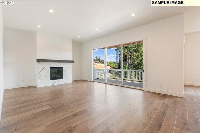 unfurnished living room with a high end fireplace and light hardwood / wood-style flooring