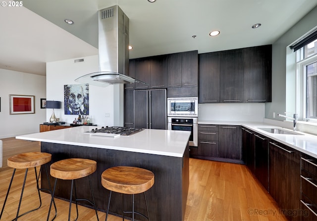 949 NW Overton St Unit 1302, Portland, OR 97209 - kitchen featuring built in appliances, island range hood, a breakfast bar, light wood-type flooring, and a center island