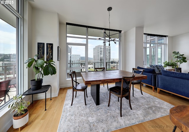 949 NW Overton St Unit 1302, Portland, OR 97209 - dining area with healthy amount of natural light, a chandelier, a view of city, light wood finished floors, and floor to ceiling windows