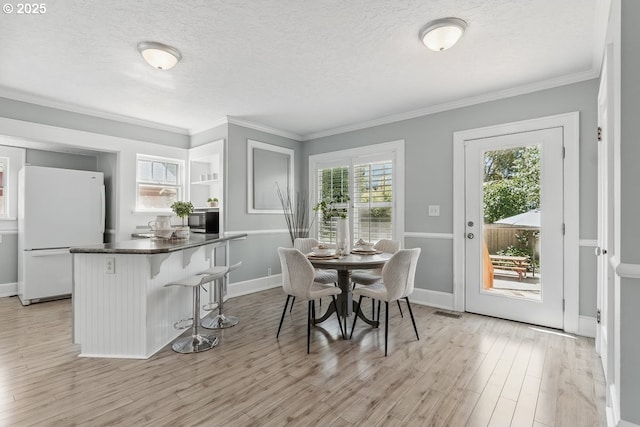 1902 N Terry St, Portland, OR 97217 - dining room with light wood finished floors, crown molding, a textured ceiling, and baseboards