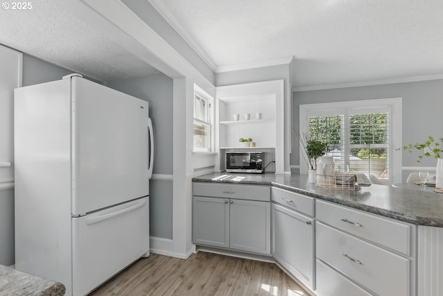 1902 N Terry St, Portland, OR 97217 - kitchen featuring freestanding refrigerator, light wood-style flooring, ornamental molding, stainless steel microwave, and baseboards