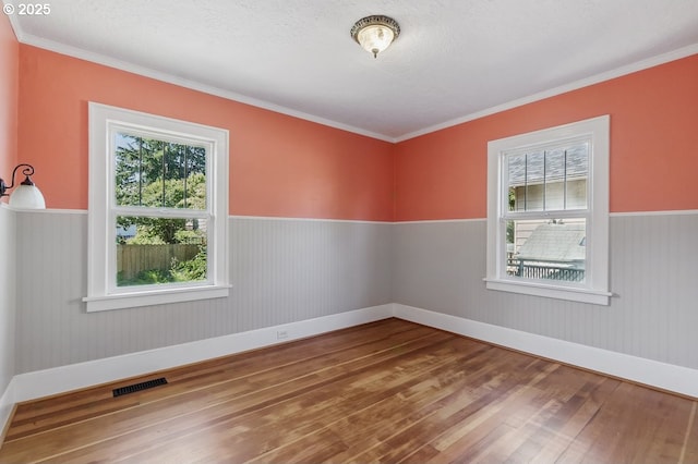 1902 N Terry St, Portland, OR 97217 - unfurnished room featuring hardwood / wood-style flooring, a wainscoted wall, baseboards, crown molding, and a textured ceiling